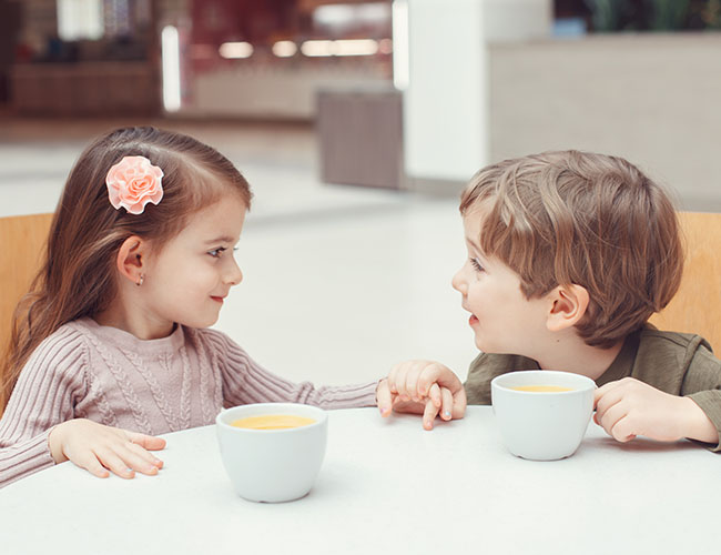 Two 3 - 4 year old children talking to each other.