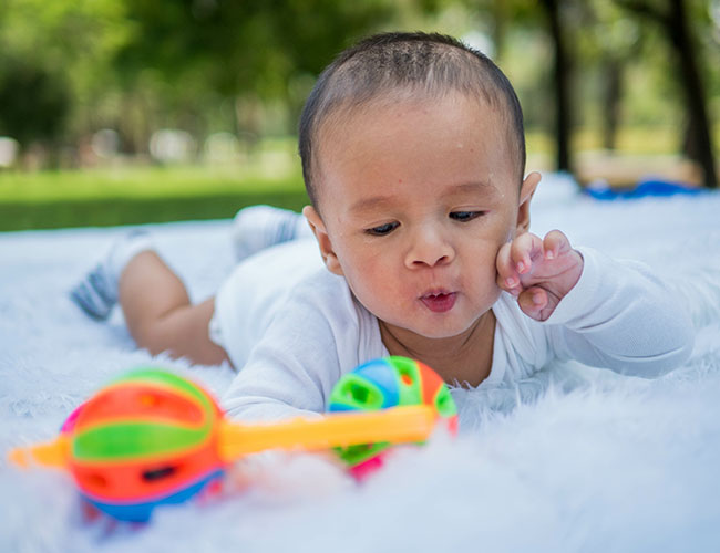 4 - 6 month old baby playing with a colorful toy.